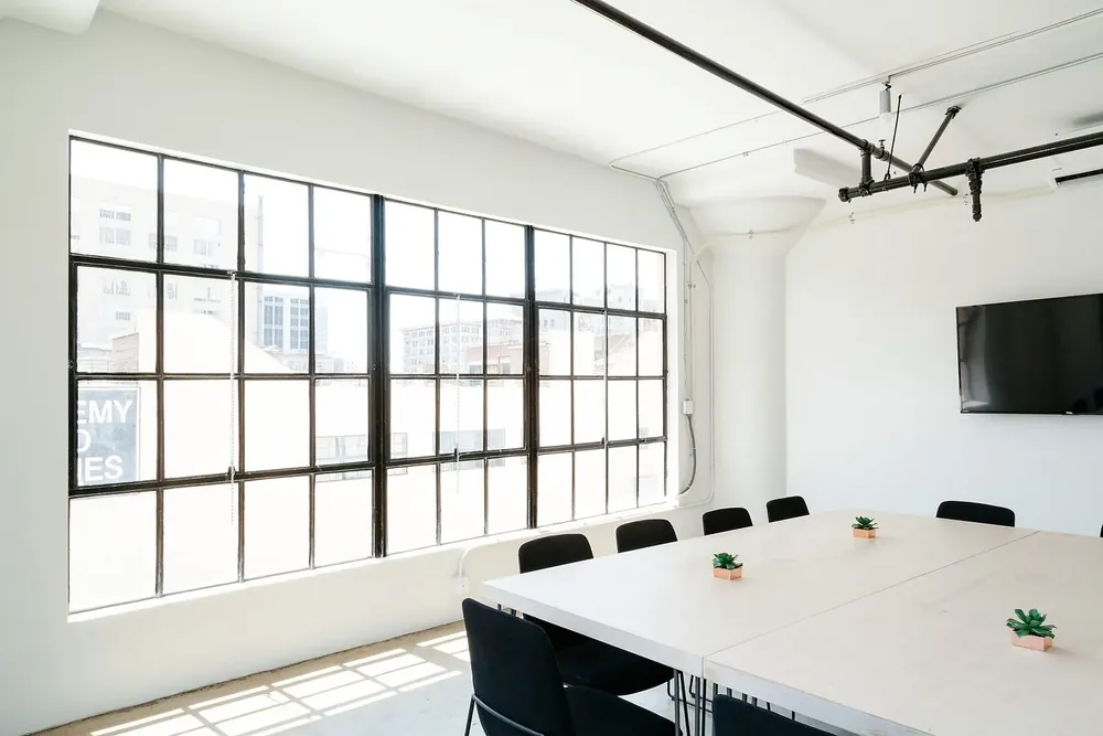 A bright meeting room with the chairs set square to a freshly wiped table
