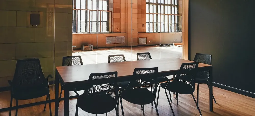 A small conference room after hours, chairs tucked in under the table